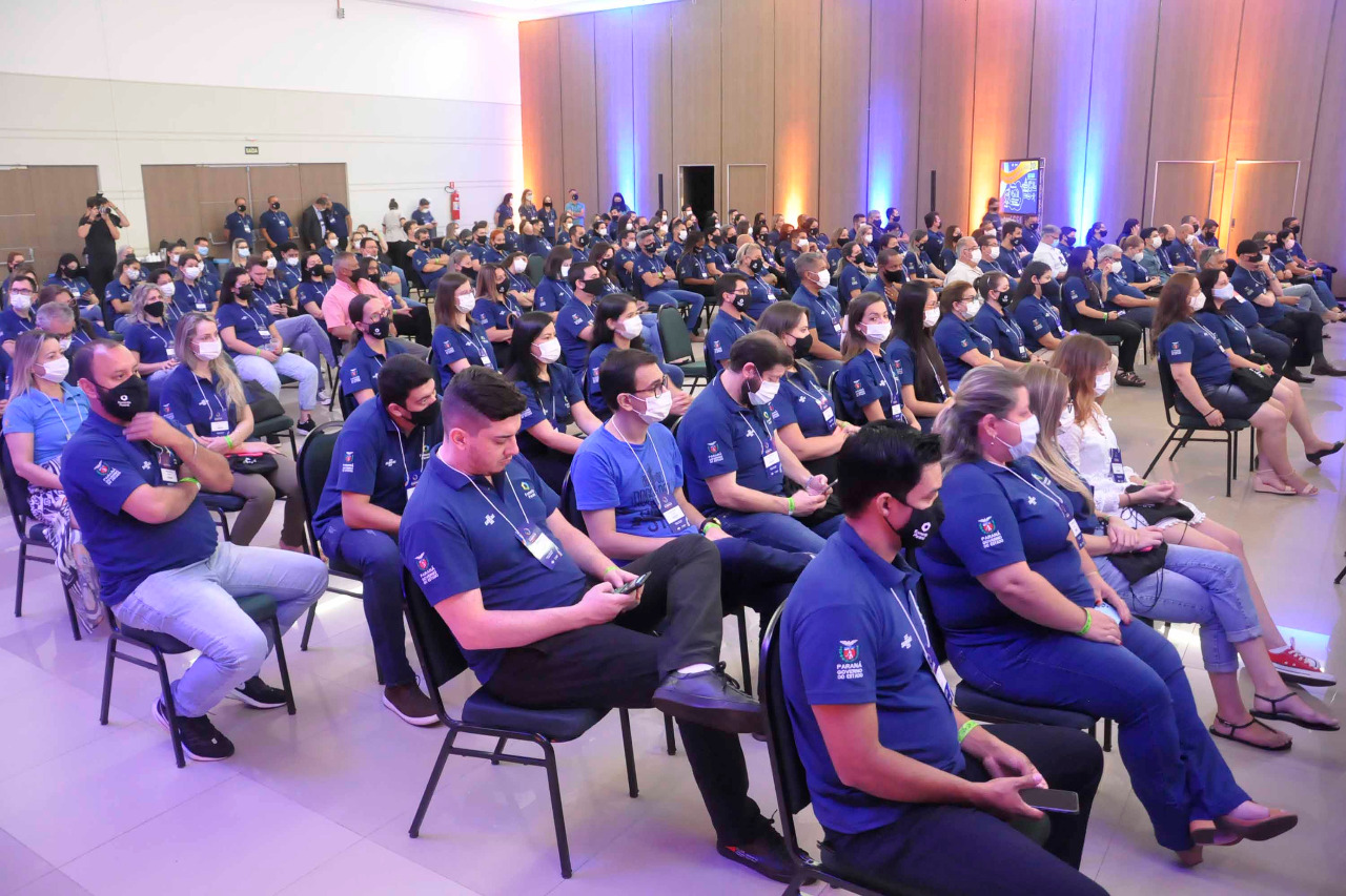 Foto mostra várias pessoas sentadas, assistindo a uma palestra.